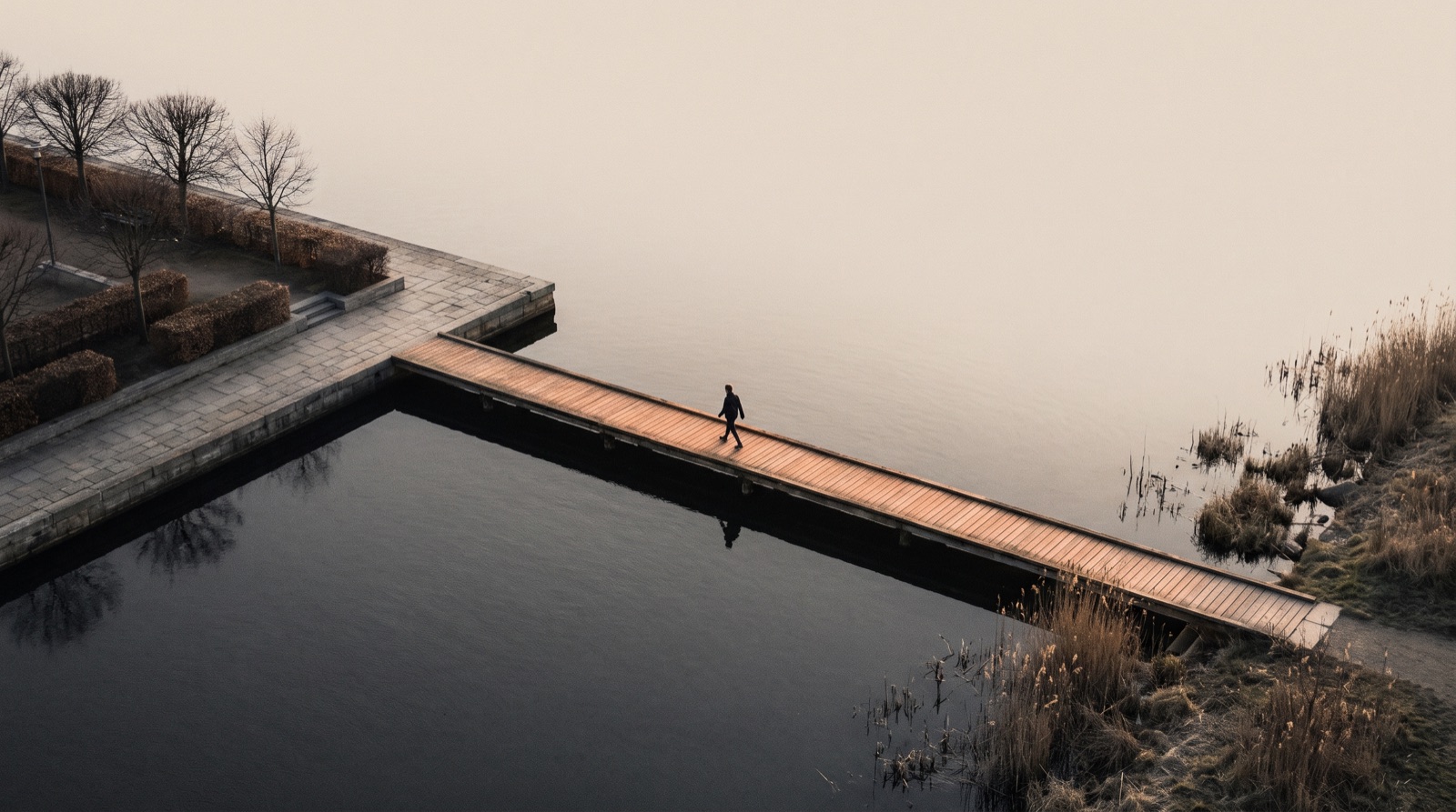 Person geht über einen Steg am Wasser